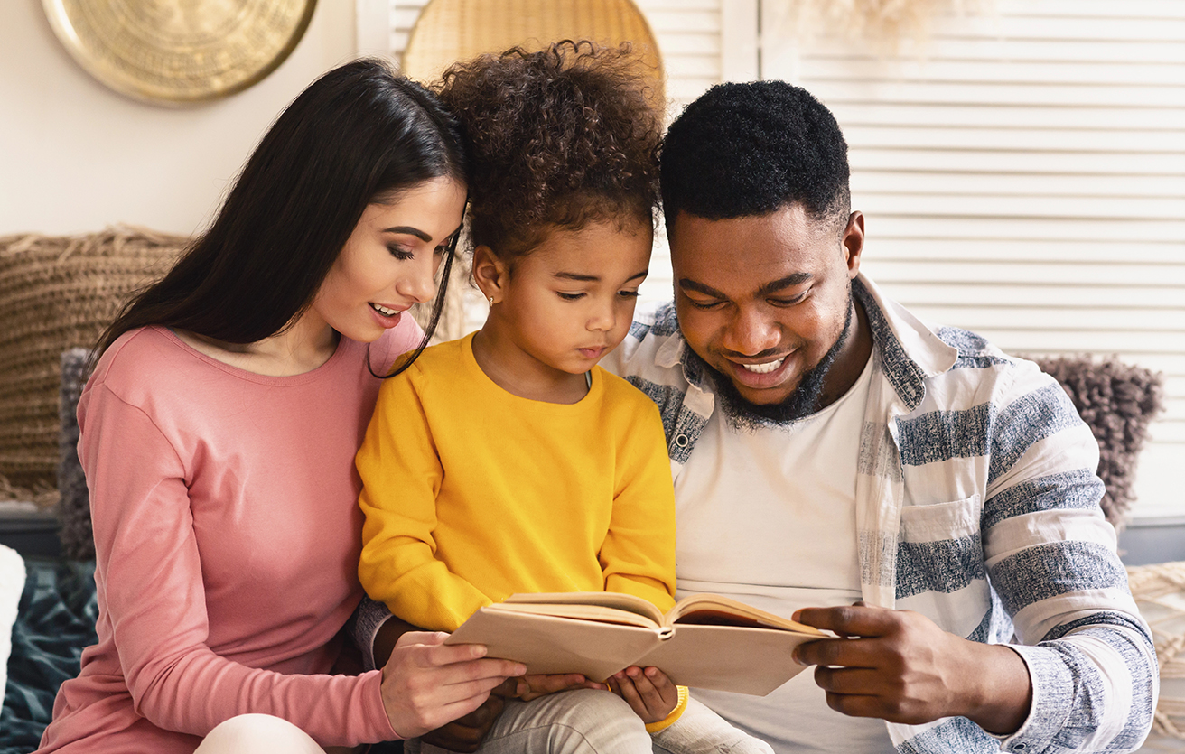 Happy family reading book together at home